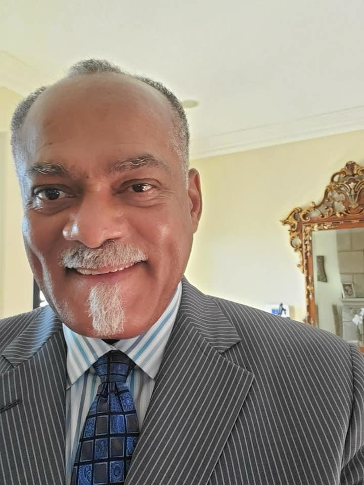 McKinley Williams smiling in a pinstripe suit and blue tie